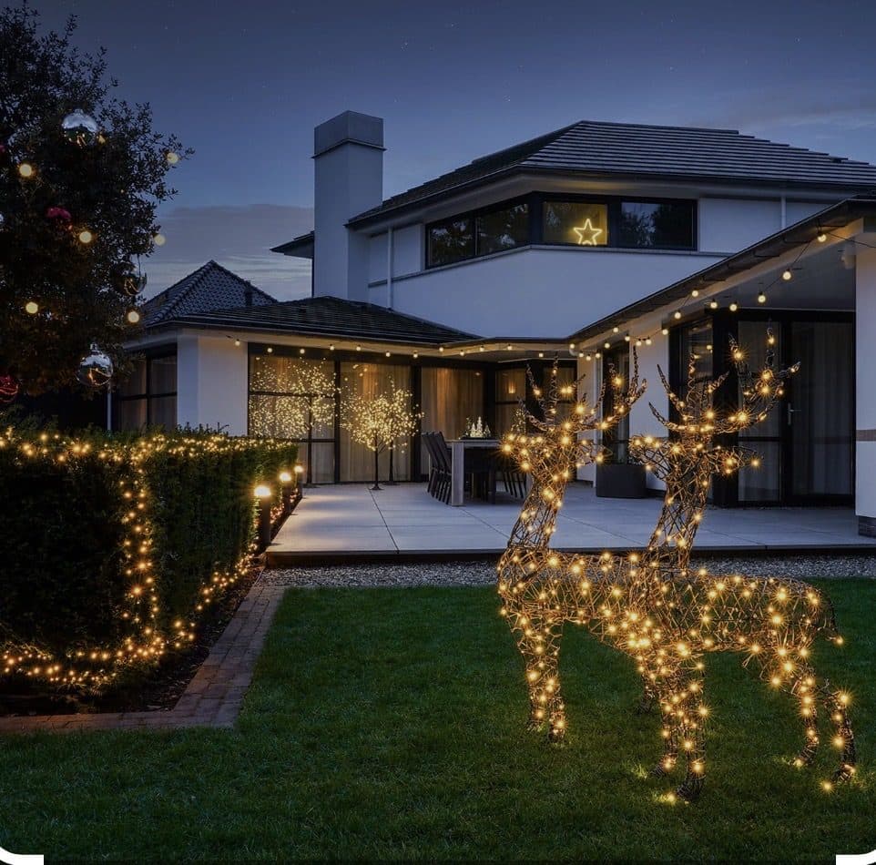 Holiday lights on a home with lit reindeer in the yard